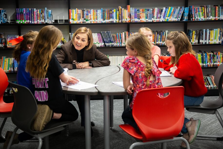 Governor Reynolds sitting with children at a library table.